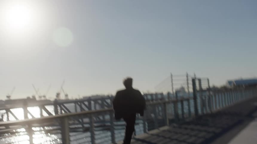 A man is running on the boardwalk by the pier