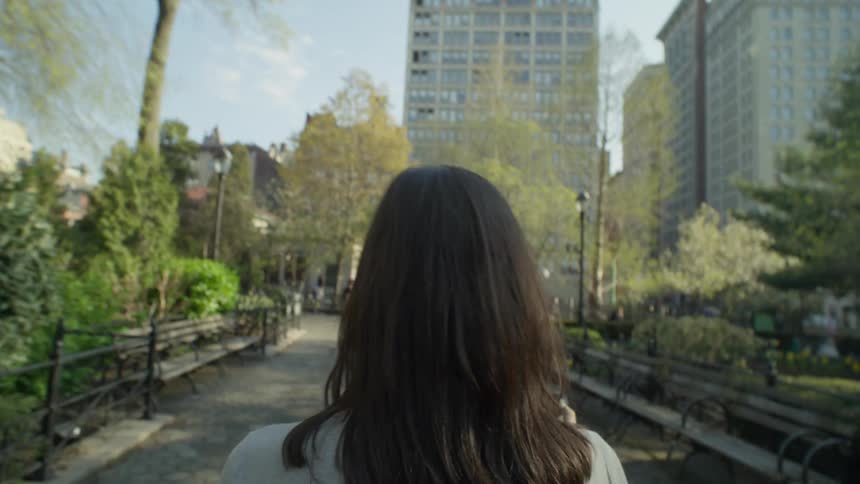 Point of view of a blackhaired woman walking in a square with buildings around her