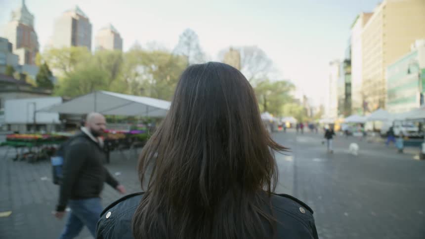 A woman walks around at a farmers market on a spring day