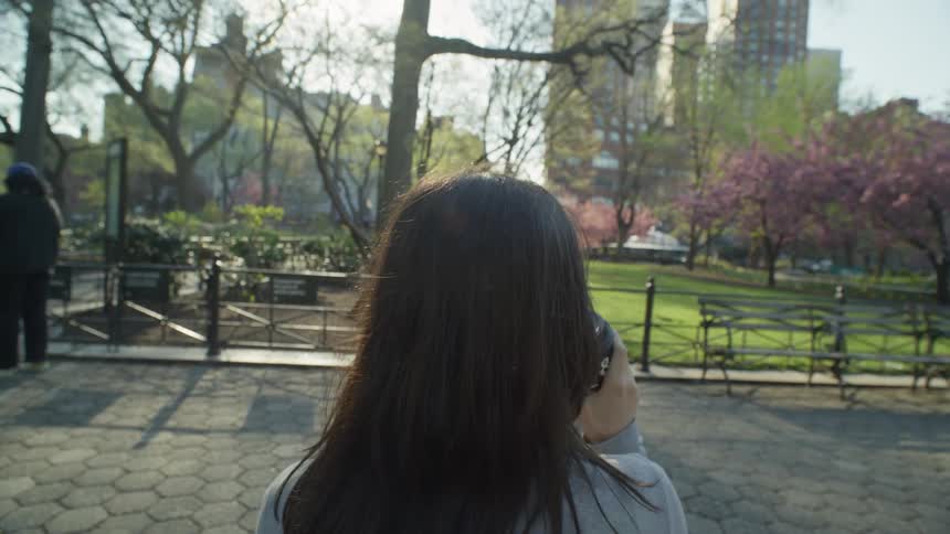 A woman drinks in a city park