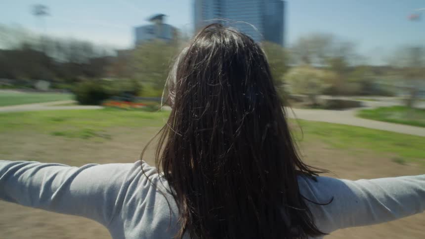 Perspective of a woman seen from behind with her arms open spinning for a view of NYC