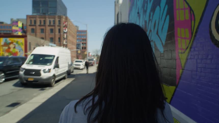 A woman is walking on the sidewalk of a New York City street