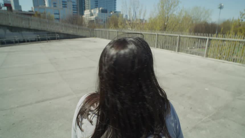 Perspective of a woman seen from behind sitting on a bench in a deserted square in a metropolis