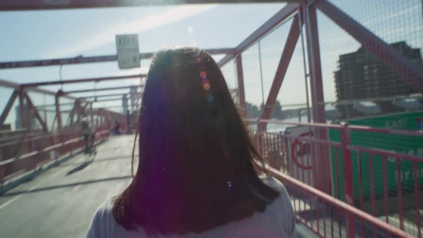Point of view of a blackhaired woman walking on a bridge through the metropolis