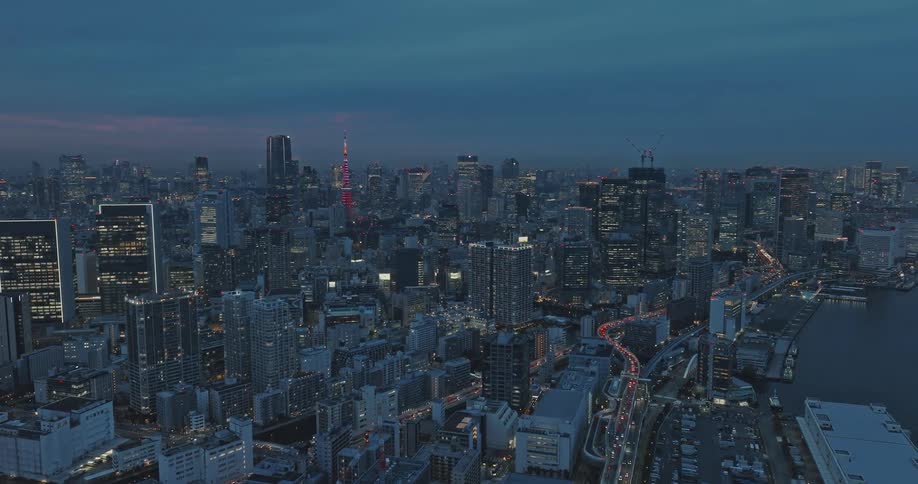 Downtown Tokyo and Tokyo Tower are illuminated as the camera orbits above the skyscrapers and freeway