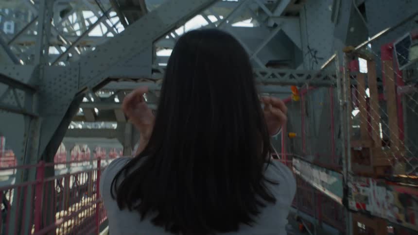 View from behind of a woman crossing a bridge in the city
