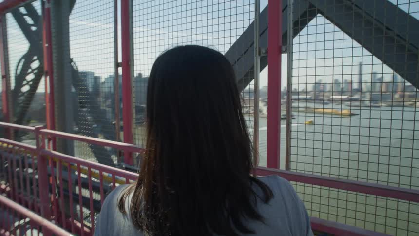 Perspective of a woman walking across the Williamsburg bridge over the East River in New York City