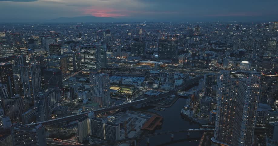 The iconic Japanese high speed Shinkansen train races through downtown Tokyo at blue hour