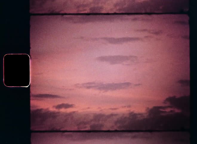 Stratus and cumulus clouds obscure the pink or red twilight evening sky during the afterglow of a beautiful and romantic sunset on vintage Super 8 film footage with retro feeling