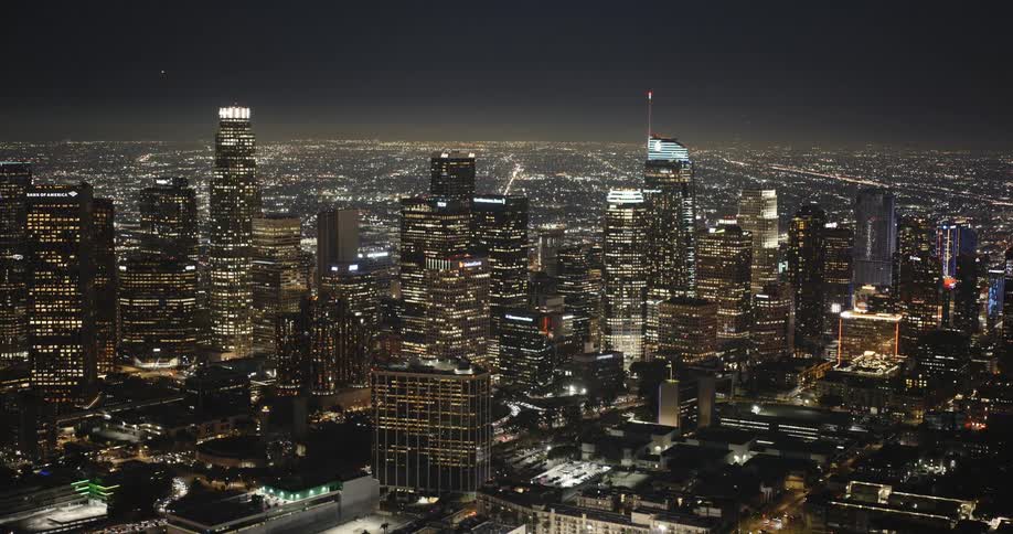 An aerial view captures the illuminated skyscrapers and buildings of downtown Los Angeles at night creating a mesmerizing cityscape
