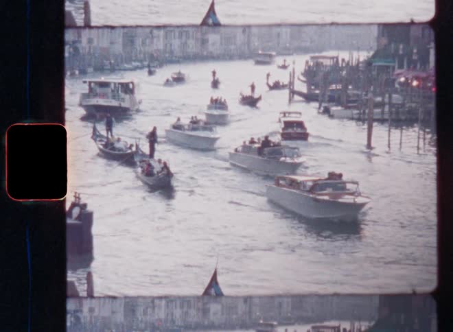 Several boats such as Venetian gondola and motorboats sailing and driving in a crowded canal with docks along the banks and a lot of water traffic in the city centre of Venice in Italy on vintage Super 8mm film