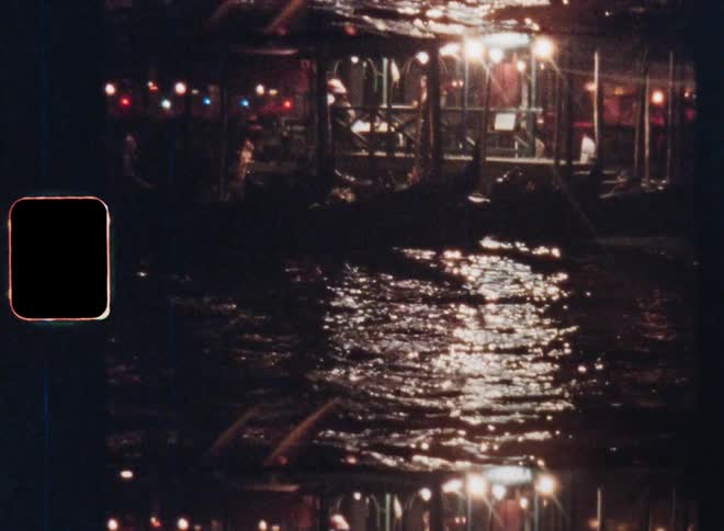 Bright spotlights or street lights from a restaurant in a harbour building illuminate water as they shine onto the canal or lake causing reflections during nighttime