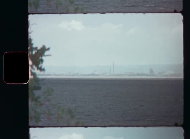 Natural landscape of the calm sea with the silhouette of a city on the horizon on a blue sky day
