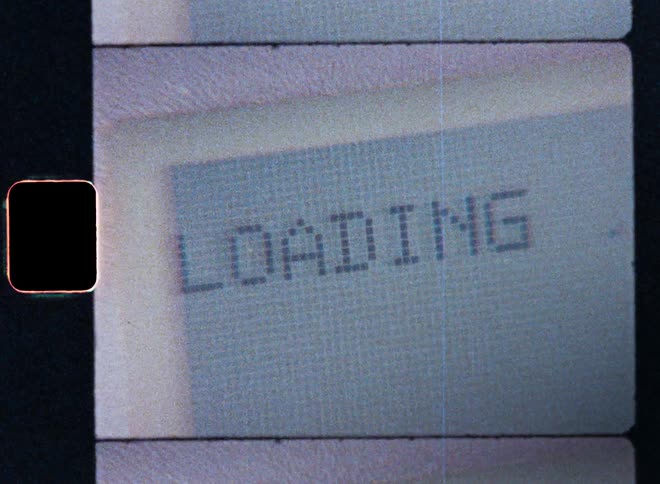 The pixelated retro display or screen of an old vintage laptop computer is displaying a loading sign during the booting process as the electrical device is starting and the PC user is waiting for his old technological machine to boot