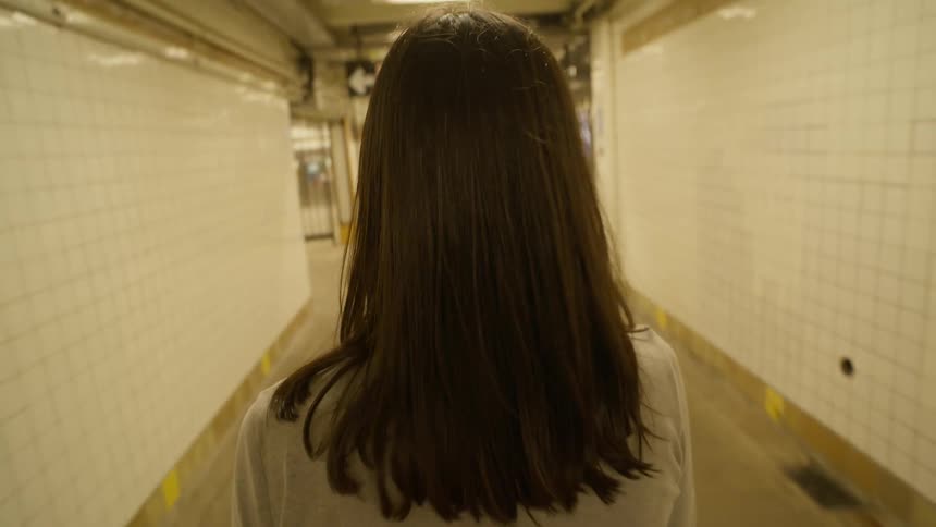 Point of view of a blackhaired woman walking in a train station