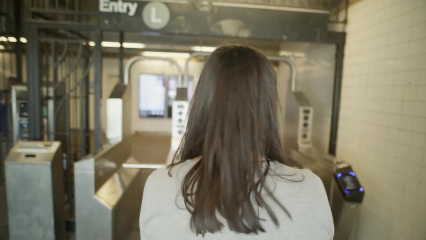 A young woman swipes through the subway turnstile