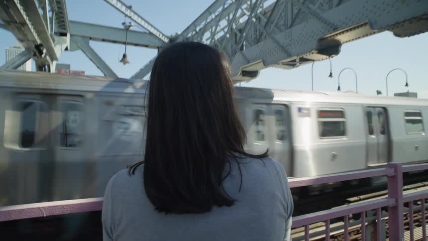 Perspective of a woman seen from behind on an overpass with a train passing by