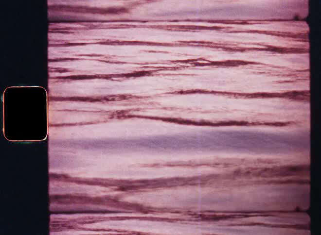 Ocean or lake water is rippling and moving due to small waves as the surface of the body of water reflects the solar sunlight during the sunset at dusk or sunrise at dawn colouring everything red or purple