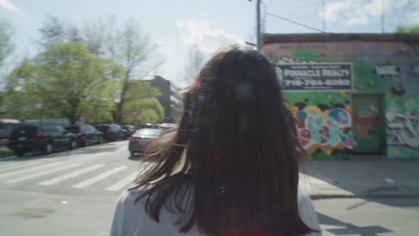 Woman walks through intersection near mural and graffiti covered buildings