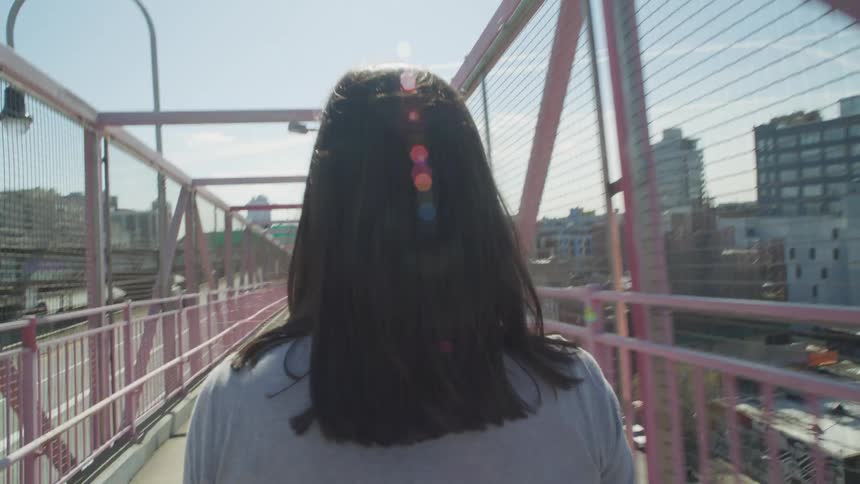 A woman walks across the Williamsburg Bridge in Brooklyn New York