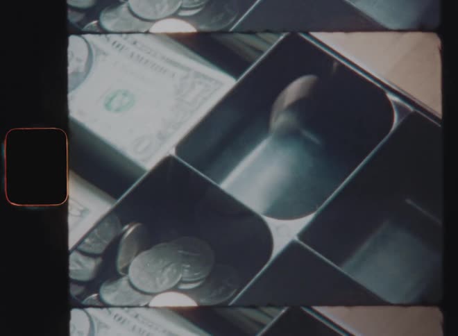 Caucasian hand pouring or throwing silver US dollar coins into the drawer of a vintage cash register after receiving the payment of a customer in his business store before closing the cash compartment to finalise the successful sale