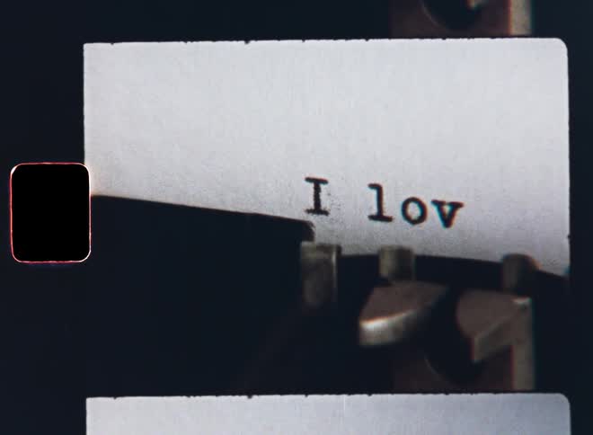 Extreme Super 8mm macro closeup of vintage mechanical typewriter machine typing the text or words I Love You on a white sheet of paper for Valentine’s Day love letter or romantic surprise present from an anonymous unknown lover