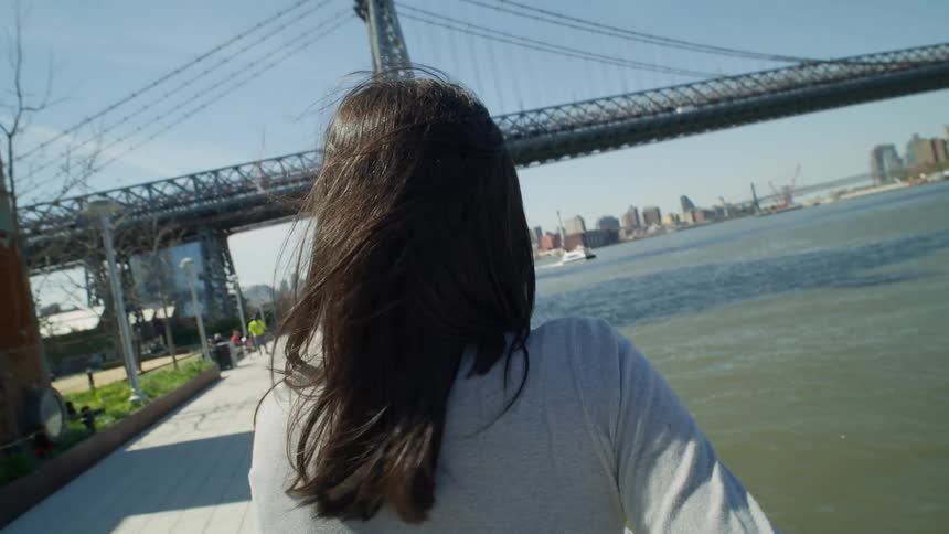 Woman leaning on a handrail views a bridge in New York City