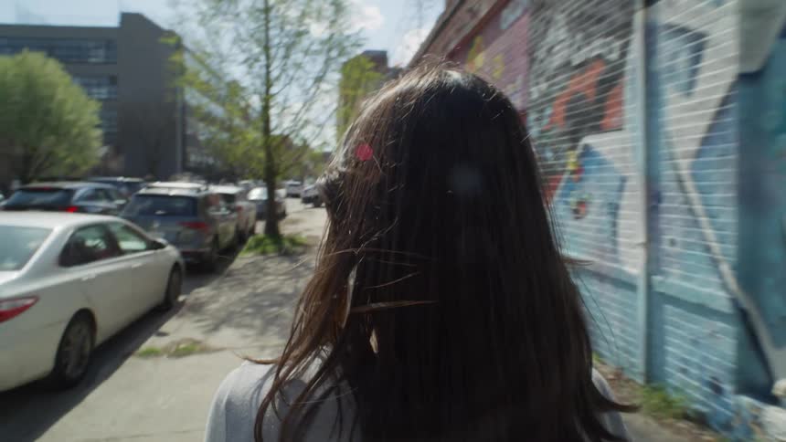 A woman examines street art on a wall as she walks in NYC