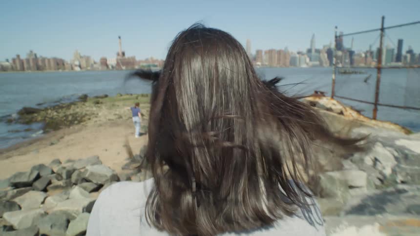 A woman with long hair observing the shoreline near New York City
