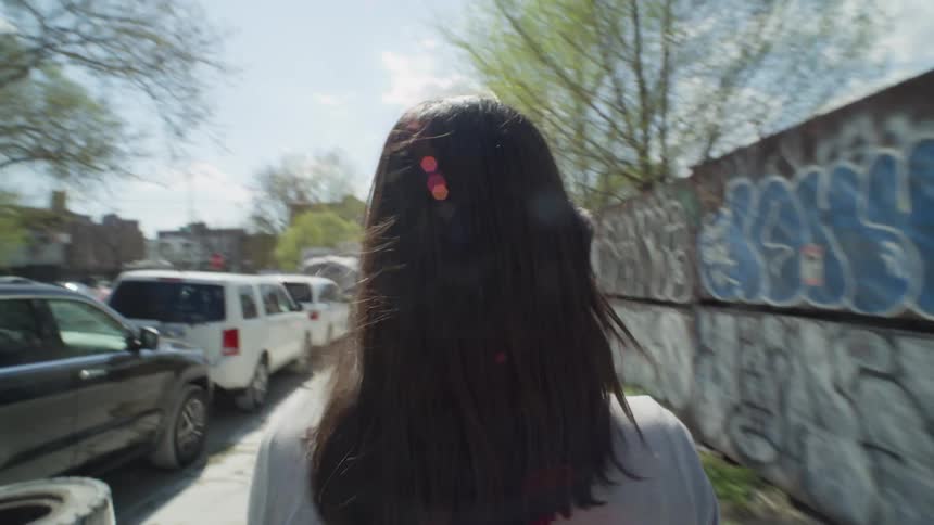 A young woman walks down an urban street with graffiti in NYC