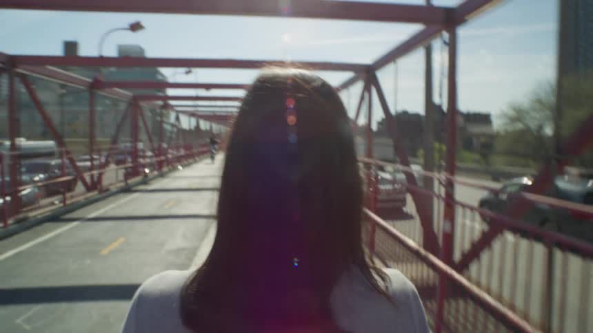 Woman seen from behind walking on the Williamsburg Bridge in New York City