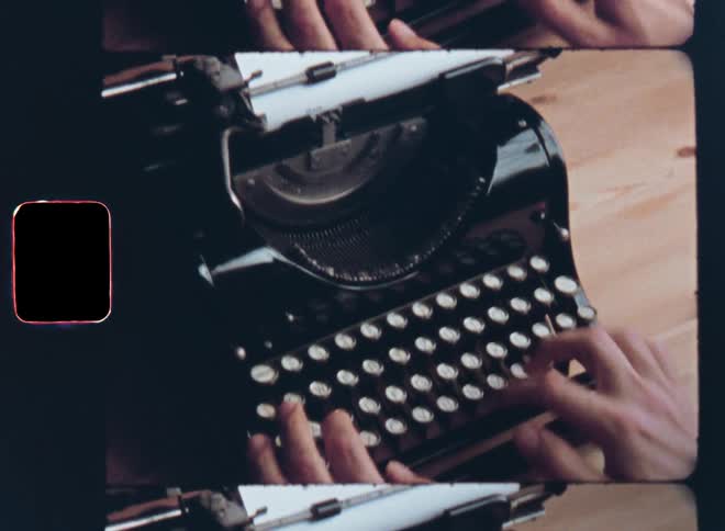 A young person in a gray shirt sits at a wooden table concentrating and contemplating before he starts typing on a black vintage typewriter with a stylish keyboard from the last century on retro Super 8mm film