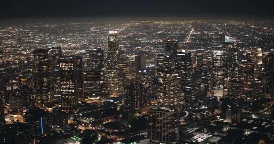 The camera slowly orbits downtown Los Angeles brightly lit at night