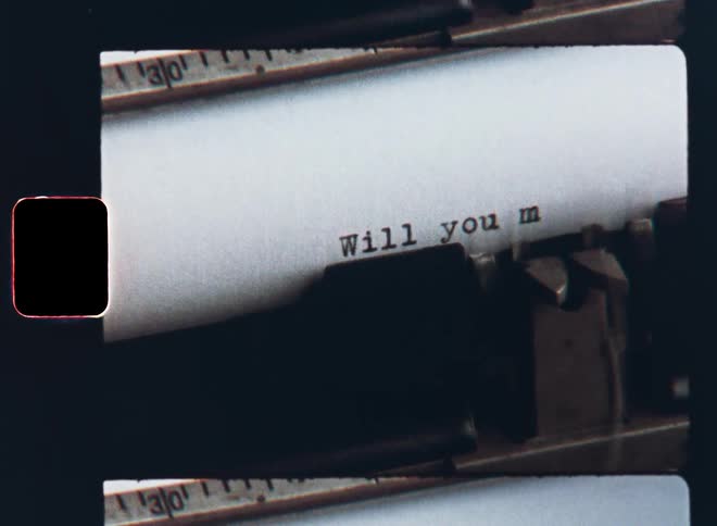 Macro closeup of an analog or mechanical typewriter typing or writing the phrase or question Will You Marry Me on a piece of paper as part of a romantic love letter for a surprise marriage proposal and declaration of love