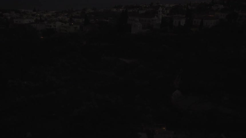 A few fireworks being shot over a dark cityscape
