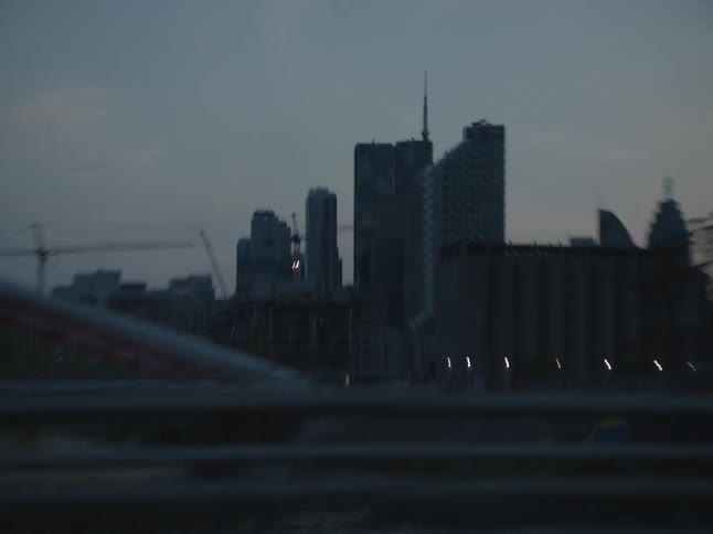 View from the window of a moving vehicle to a metropolis with skyscrapers on a dark morning