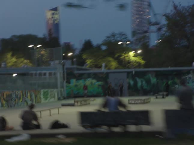 People visit a city skate park decorated with graffiti at night