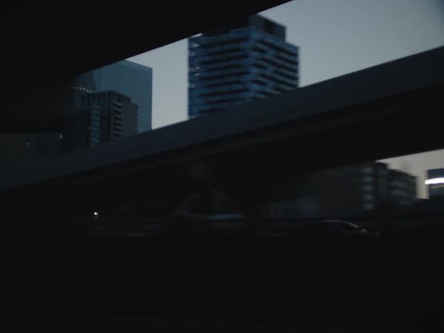 Vehicle moves down descending highway near downtown skyscrapers
