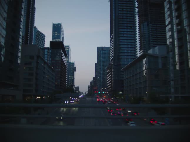 View of large buildings in a metropolis with intersections having vehicle traffic at dusk
