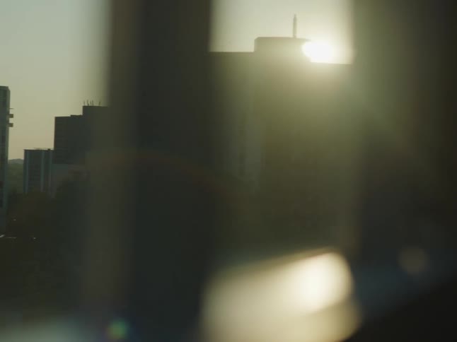 A cityscape at sunset with buildings silhouetted against the glowing sky