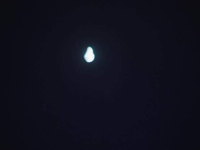 The quarter moon shines in the night sky observed from a car driving on a road