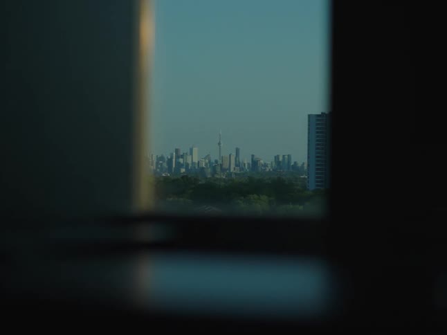 A cityscape through a window with a twilight sky
