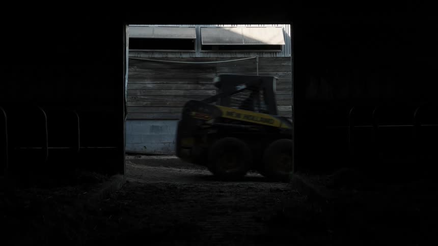 Operator drives bulldozer past opening in the building