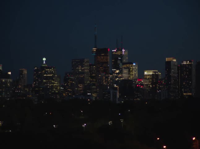 The city skyline at night glows with a mesmerizing display of warm and colored lights illuminating the buildings