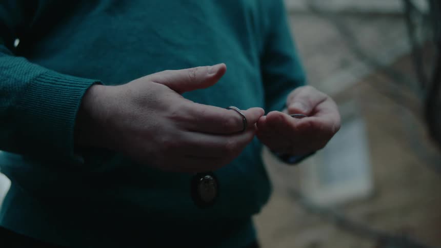 A person standing in front of a house takes a key out of a keyring