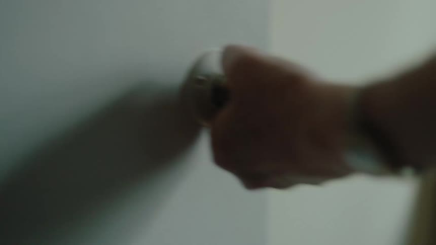 Closeup of a mans hand holding the doorknob and opening the door