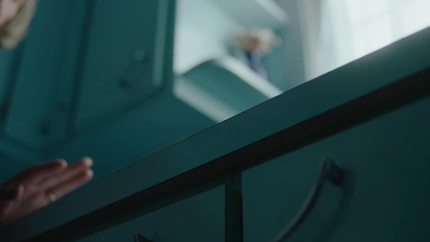 Closeup of a toy car falling from a kitchen cabinet propelled by a hand