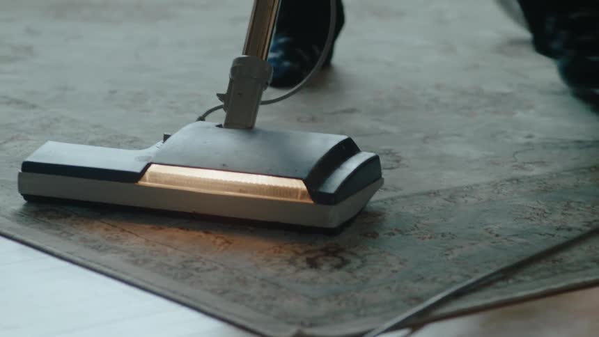 A person vacuums a rug