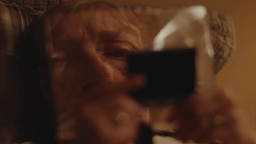 The face of an elderly person who is seeing himself in a small mirror