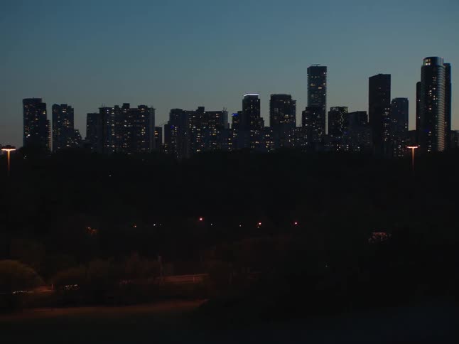 Panorama of pedestrians and vehicle traffic in time lapse and in the background a metropolis with a skyscraper illuminated at dusk
